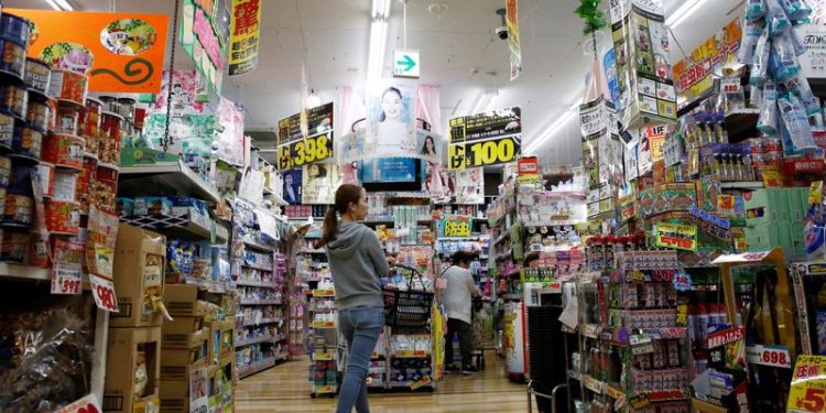 Japan says overall economy recovering, cuts view on corporate profits